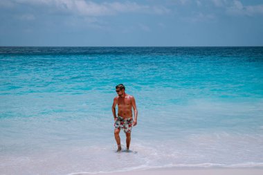 La Digue Seyşeller, tropik ada La Digue 'da tatilde olan genç erkekler, tropik sahil Seyşelleri' nde tatilde sahilde yürüyen orta yaşlı bir adam.