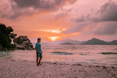 La Digue Seyşeller, tropik ada La Digue 'da tatilde olan genç erkekler, tropik sahil Seyşelleri' nde tatilde sahilde yürüyen orta yaşlı bir adam.