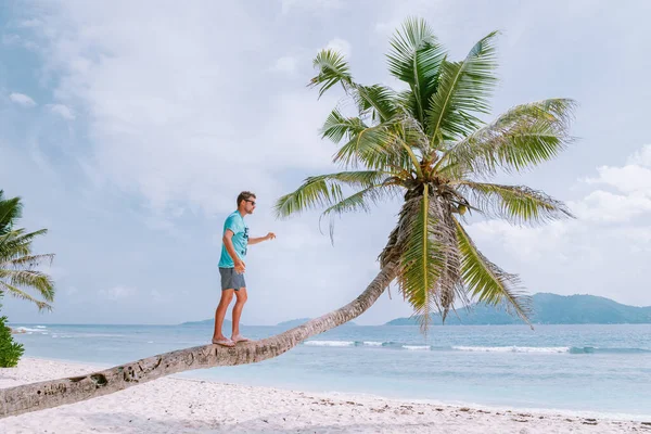 在塞舌尔热带岛屿La Digue度假的年轻人，在塞舌尔热带海滩度假期间在海滩散步的中年男子 — 图库照片