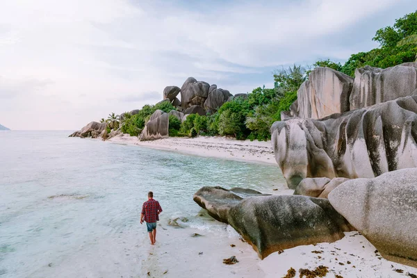 La Digue Σεϋχέλλες, νέοι άνδρες σε διακοπές στο τροπικό νησί La Digue, μεσήλικας τύπος περπάτημα στην παραλία κατά τη διάρκεια των διακοπών στην τροπική παραλία Σεϋχέλλες — Φωτογραφία Αρχείου