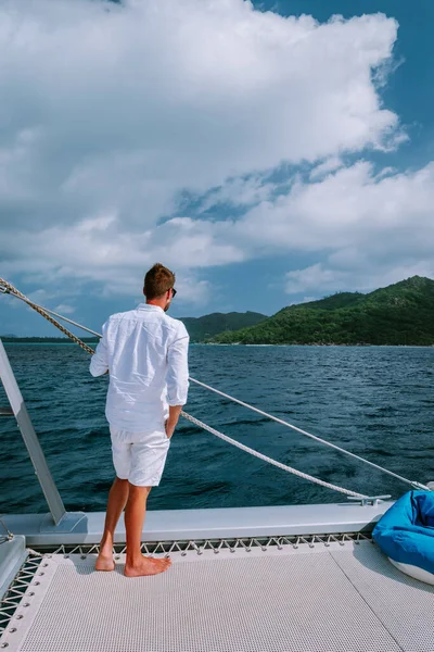 젊은 남자들은 돛단배 세이셸 열대 섬에서 휴가를 보내고 있습니다. 바다에서 돛단배를 타고 출근길에 있는 중년 남자입니다. — 스톡 사진