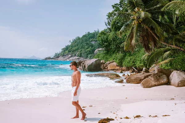 La Digue Seychely, mladí muži na dovolené na tropickém ostrově La Digue, muž středního věku procházky na pláži během dovolené na tropické pláži Seychely — Stock fotografie