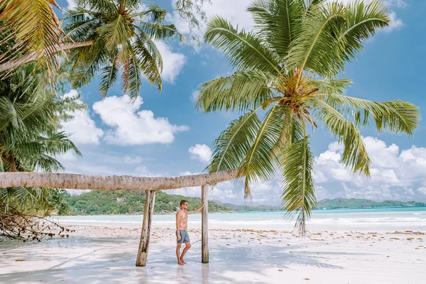 Cote dOr Beach Praslin Seychellerna, unga medelålders män i simma kort promenad på stranden under semester Secyhelles tropiska ön, vit kille på stranden under semestern Praslin — Stockfoto