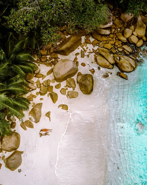 Praia branca tropical na ilha de Praslin Seychelles, feliz casal jovem homem e mulher durante as férias Férias na praia relaxando sob uma palmeira — Fotografia de Stock