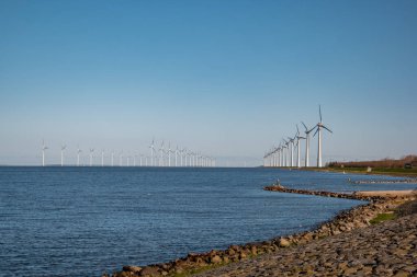 Okyanus açıklarındaki yel değirmeni çiftliği Westermeerwind Parkı 'ndaki yel değirmenleri Hollanda Flevoland Noordoostpolder' ın güneşli bir gününde denizde izole edilmiş.