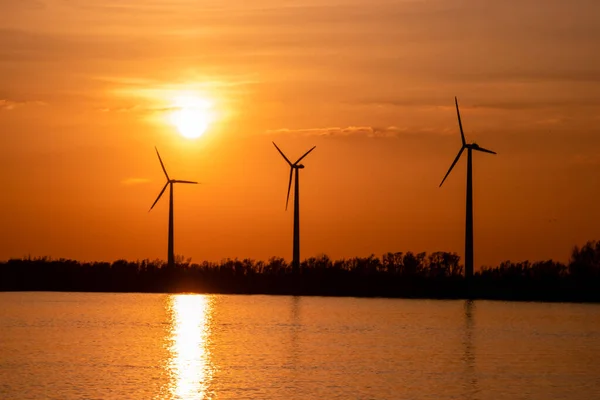 Moerdijk Netherlands, sunset winth windmills by the lake Vokerak river in Holland windmill energy sunset