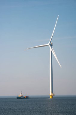 Yel değirmeni parkı Batı Hollanda, rüzgâr değirmeni türbini okyanusta mavi gökyüzü, yeşil enerji