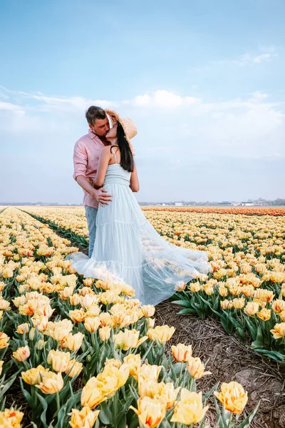 Tulip flower field during sunset dusk in the Netherlands Noordoostpolder Europe, happy young couple men and woman with dress posing in flower field in the Netherlands — Stock Photo, Image