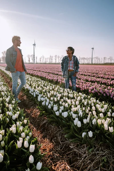 Tulip flower field during sunset dusk in the Netherlands Noordoostpolder Europe, happy young couple men and woman with dress posing in flower field in the Netherlands — Stock Photo, Image