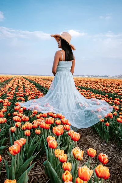 Hollanda 'daki lale çiçeği tarlası, lale çiçeği tarlasında elbisesi ve çiçekli şapkası olan genç bir kadın. — Stok fotoğraf