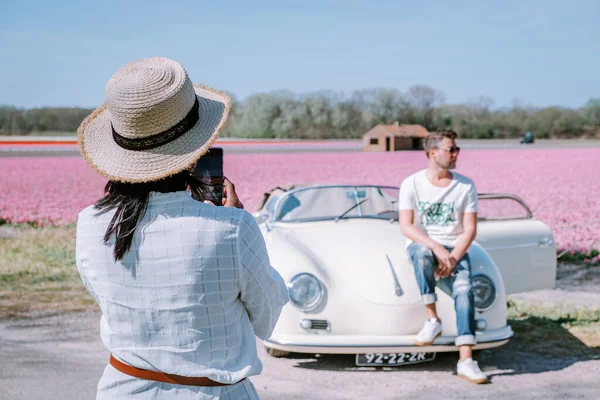 Lisse Holandia. para robi wycieczkę ze starym zabytkowym samochodem sportowym White Porsche 356 Speedster, holenderski region kwiatowy żarówki z polami tulipanów — Zdjęcie stockowe