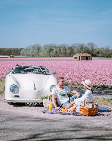 Lisse Holandia. para robi wycieczkę ze starym zabytkowym samochodem sportowym White Porsche 356 Speedster, holenderski region kwiatowy żarówki z polami tulipanów — Zdjęcie stockowe