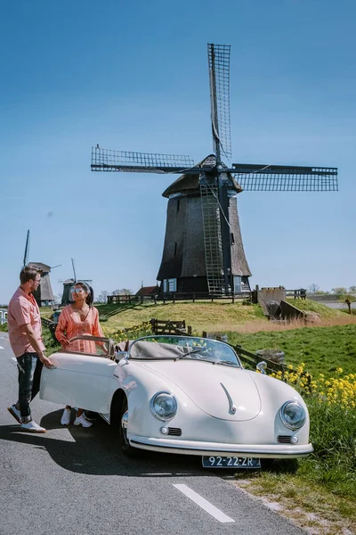 Schermerhorn Alkmaar Netherlands April 2020,. couple doing a road trip with a old vintage sport car White Porsche 356 Speedster, Dutch windmill village Schermerhorn — Stock Photo, Image