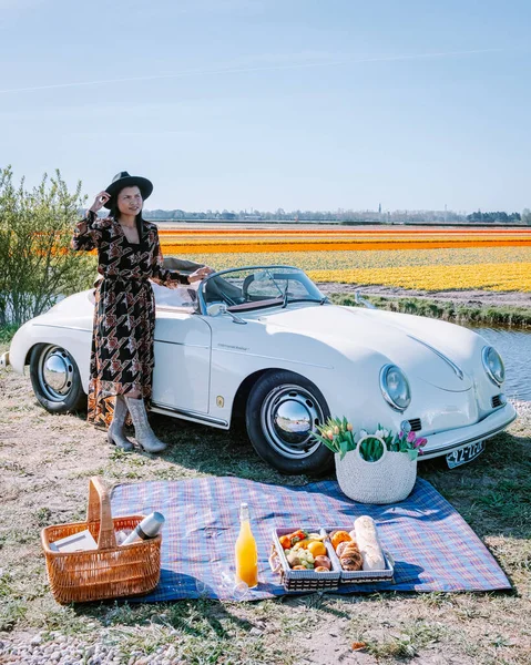 Lisse Netherlands,. casal fazendo uma viagem com um velho carro esporte vintage Branco Porsche 356 Speedster, holandês região bulbo flor com campos de tulipa — Fotografia de Stock