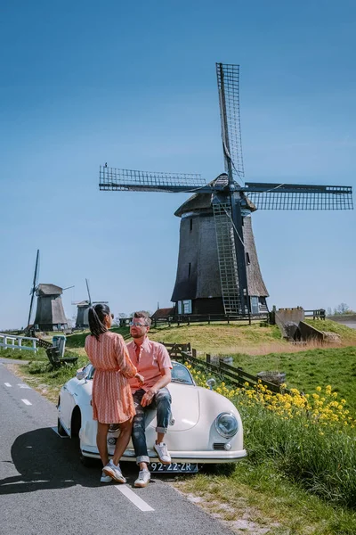Schermerhorn Alkmaar Netherlands April 2020,. Пара подорожує по дорозі з старовинним спортивним автомобілем White Porsche 356 Speedster, голландським вітровим селом Schermerhorn — стокове фото