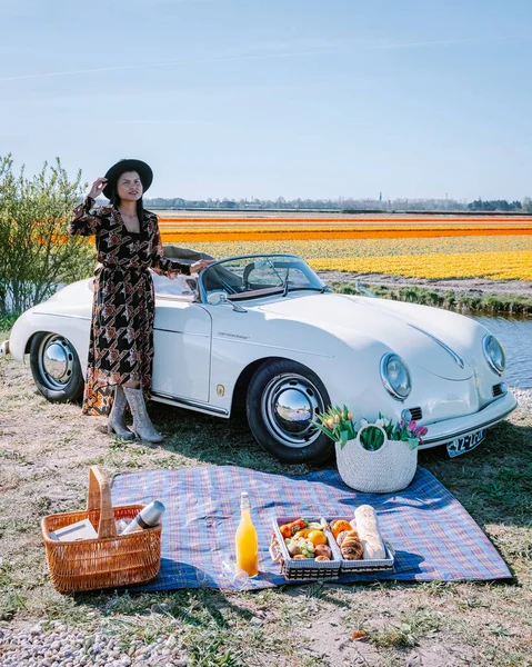 Lisse Netherlands,. casal fazendo uma viagem com um velho carro esporte vintage Branco Porsche 356 Speedster, holandês região bulbo flor com campos de tulipa — Fotografia de Stock