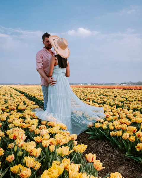 Couple men and woman in flower field in the Netherlands during Spring, orange red tulips field near Noordoostpolder Flevoland Netherlands, men and woman in Spring evening sun — Stock Photo, Image