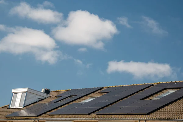Nově postavené domy v Nizozemsku se solárními panely připevněnými na střeše proti slunné obloze Close up of new building black solar panels — Stock fotografie