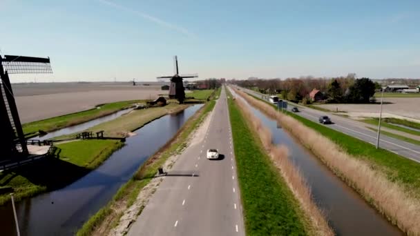 Schermerhorn Alkmaar Netherlands Апрель 2020,. Пара, путешествующая со старым винтажным спортивным автомобилем White Porsche 356 Speedster, голландская ветряная мельница деревня Шермерхорн — стоковое видео