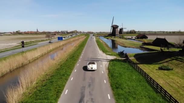 Schermerhorn Alkmaar Ολλανδία Απρίλιος 2020,. ζευγάρι κάνει ένα οδικό ταξίδι με ένα παλιό αυτοκίνητο αντίκα σπορ White Porsche 356 Speedster, ολλανδικό χωριό ανεμόμυλος Schermerhorn — Αρχείο Βίντεο