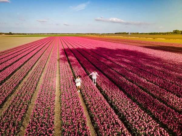 Pareja de hombres y mujeres en el campo de flores en los Países Bajos durante la primavera, campo de tulipanes rojos anaranjados cerca de Noordoostpolder Flevoland Países Bajos, hombres y mujeres en el sol de la noche de primavera — Foto de Stock