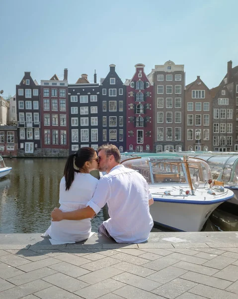 Pareja en un viaje a Ámsterdam, hombres y mujeres relajándose junto a los canales de Ámsterdam durante la primavera 2020 abril en Europa Países Bajos —  Fotos de Stock