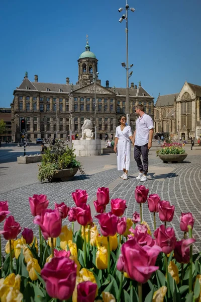 Koppel op een stedentrip naar Amsterdam, mannen en vrouwen ontspannen aan de grachten van Amsterdam in het voorjaar van 2020 april in Europa Nederland — Stockfoto