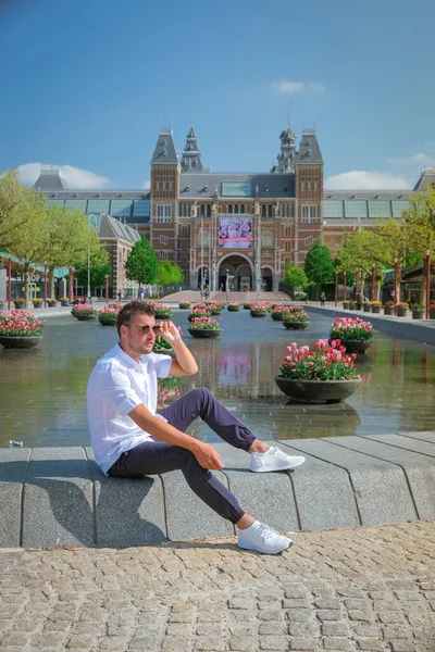 Amsterdam Holandia kwiecień 2020, prawie pusty plac Amsterdam Rijksmuseum podczas epidemii wirusa Corona covid 19 w Europie z wiosennymi tulipanami przed muzeum — Zdjęcie stockowe