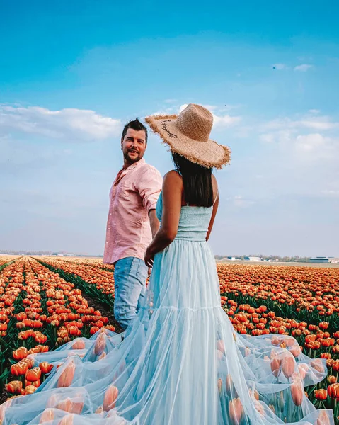 Paar wandelen in bloemenveld in het voorjaar in Nederland, jongen en meisje in Tulpenveld, mannen en vrouw in kleurrijke bloemenlijnen in de Noordoostpolder Holland — Stockfoto