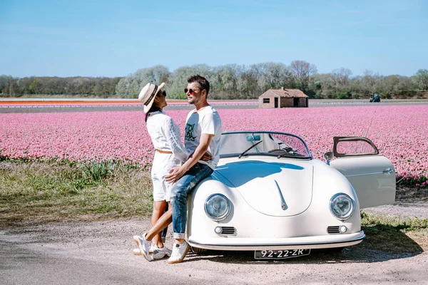 Lisse Netherlands,. casal fazendo uma viagem com um velho carro esporte vintage Branco Porsche 356 Speedster, holandês região bulbo flor com campos de tulipa — Fotografia de Stock
