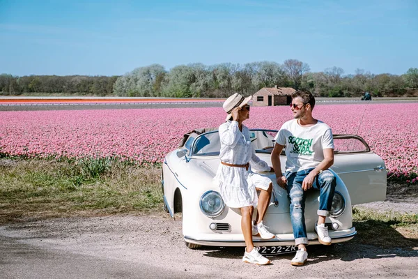 Lisse Netherlands,. casal fazendo uma viagem com um velho carro esporte vintage Branco Porsche 356 Speedster, holandês região bulbo flor com campos de tulipa — Fotografia de Stock