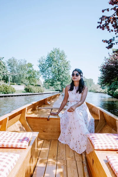 Giethoorn Países Bajos mujer visita el pueblo con un barco, vista de la famosa aldea con canales y casas de techo de paja rústica en la zona de la granja en un día de primavera caliente — Foto de Stock