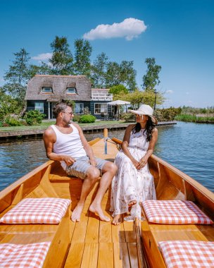 Giethoorn Hollandalı çift, sıcak bir bahar günü çiftlikte, kanallı ve sazdan çatı evleriyle ünlü köy manzaralı bir tekneyle köyü ziyaret ediyor.