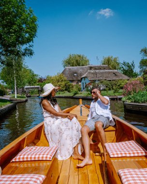 Giethoorn Hollandalı çift, sıcak bir bahar günü çiftlikte, kanallı ve sazdan çatı evleriyle ünlü köy manzaralı bir tekneyle köyü ziyaret ediyor.