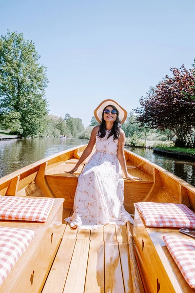 Giethoorn Países Bajos mujer visita el pueblo con un barco, vista de la famosa aldea con canales y casas de techo de paja rústica en la zona de la granja en un día de primavera caliente — Foto de Stock