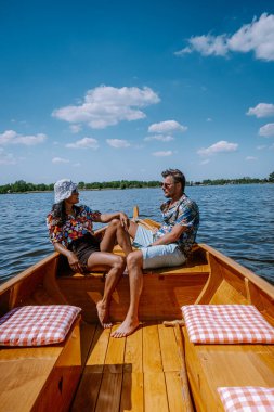 Giethoorn Hollandalı çift, sıcak bir bahar günü çiftlikte, kanallı ve sazdan çatı evleriyle ünlü köy manzaralı bir tekneyle köyü ziyaret ediyor.