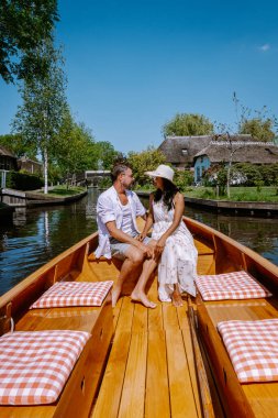 Giethoorn Hollandalı çift, sıcak bir bahar günü çiftlikte, kanallı ve sazdan çatı evleriyle ünlü köy manzaralı bir tekneyle köyü ziyaret ediyor.