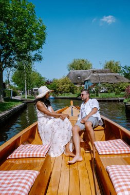Giethoorn Hollandalı çift, sıcak bir bahar günü çiftlikte, kanallı ve sazdan çatı evleriyle ünlü köy manzaralı bir tekneyle köyü ziyaret ediyor.