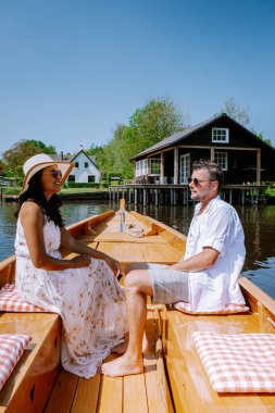 Giethoorn Hollandalı çift, sıcak bir bahar günü çiftlikte, kanallı ve sazdan çatı evleriyle ünlü köy manzaralı bir tekneyle köyü ziyaret ediyor.