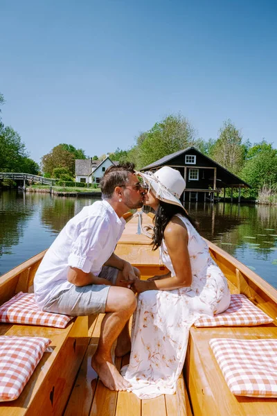 Giethoorn Nizozemsko pár navštívit vesnici s lodí, pohled na slavnou vesnici s kanály a rustikální doškovou střechou domů na farmě v horkém jarním dni — Stock fotografie