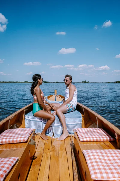 Giethoorn pareja holandesa visita el pueblo con un barco, vista del famoso pueblo con canales y casas rústicas con techo de paja en la zona de la granja en un día de primavera caliente — Foto de Stock