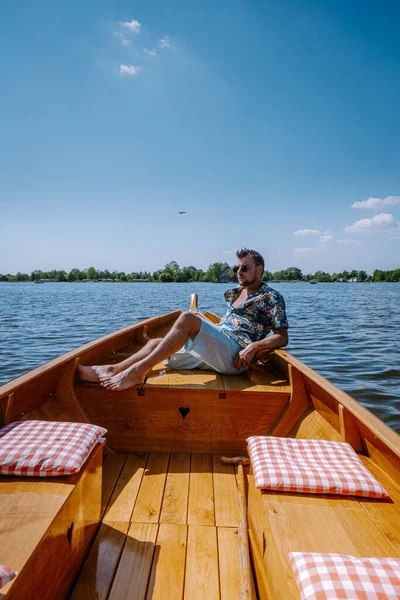 オランダ人男性がボートで村を訪れ、温泉の日には運河と素朴な茅葺き屋根の家がある有名な村の景色 — ストック写真