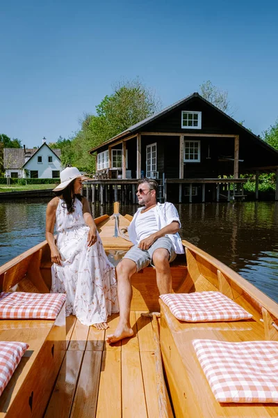 Giethoorn Holanda casal visitar a aldeia com um barco, vista da famosa aldeia com canais e casas de telhado de palha rústica na área da fazenda em um dia de primavera quente — Fotografia de Stock