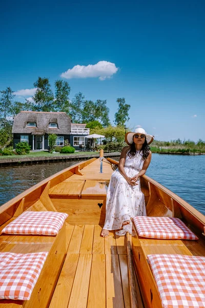 Giethoorn Netherlands woman visit the village with a boat, view of famous village with canals and rustic thatched roof houses in farm area on a hot Spring day — стоковое фото