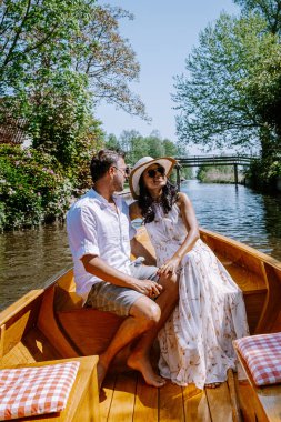 Giethoorn Hollandalı çift, sıcak bir bahar günü çiftlikte, kanallı ve sazdan çatı evleriyle ünlü köy manzaralı bir tekneyle köyü ziyaret ediyor.