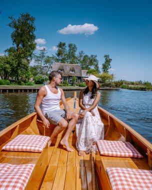 Giethoorn Hollandalı çift, sıcak bir bahar günü çiftlikte, kanallı ve sazdan çatı evleriyle ünlü köy manzaralı bir tekneyle köyü ziyaret ediyor.