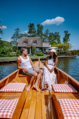 Giethoorn Hollandalı çift, sıcak bir bahar günü çiftlikte, kanallı ve sazdan çatı evleriyle ünlü köy manzaralı bir tekneyle köyü ziyaret ediyor.