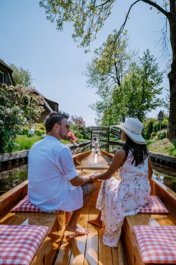 Giethoorn Hollandalı çift, sıcak bir bahar günü çiftlikte, kanallı ve sazdan çatı evleriyle ünlü köy manzaralı bir tekneyle köyü ziyaret ediyor.