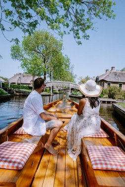 Giethoorn Hollandalı çift, sıcak bir bahar günü çiftlikte, kanallı ve sazdan çatı evleriyle ünlü köy manzaralı bir tekneyle köyü ziyaret ediyor.