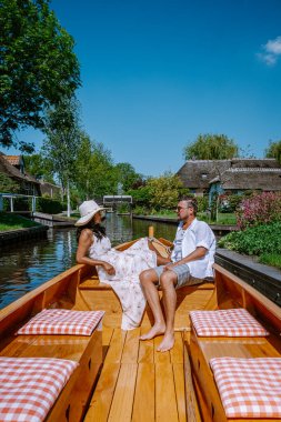 Giethoorn Hollandalı çift, sıcak bir bahar günü çiftlikte, kanallı ve sazdan çatı evleriyle ünlü köy manzaralı bir tekneyle köyü ziyaret ediyor.